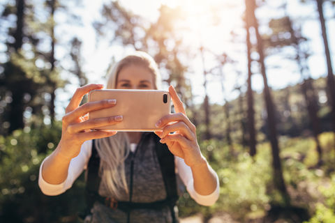 Woman taking photograph using a mobile phone during trekking. 